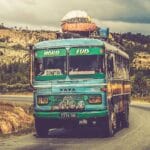 Kolorowy zabytkowy autobus jedzie wiejską drogą pod pochmurnym niebem