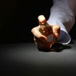 Dłoń trzymająca elegancki flakon perfum na ciemnym tle