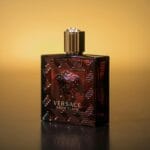 Flakon perfum Versace Eros Flame na tle ciepłego żółtego koloru