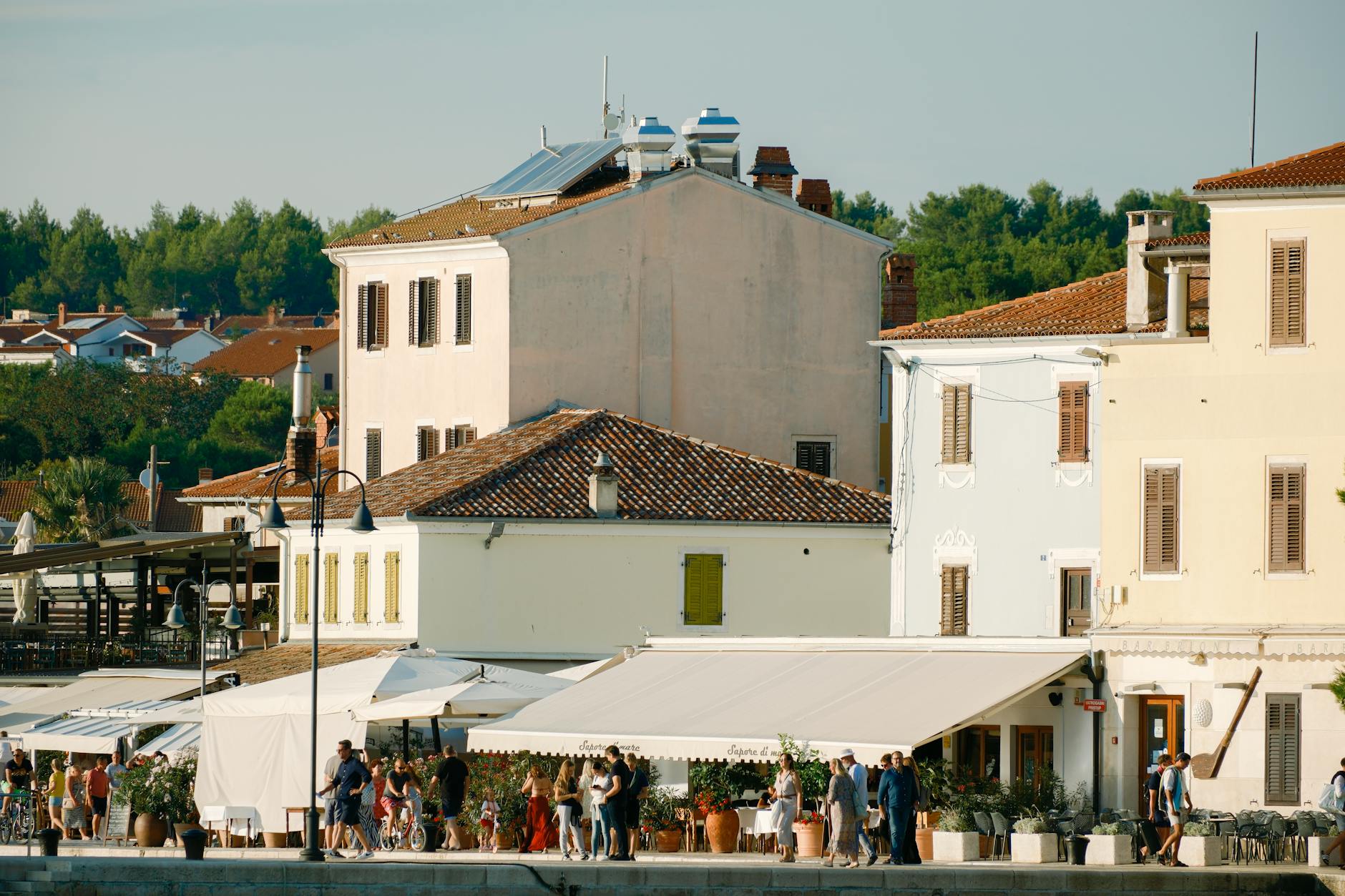 Nadmorskie zabudowania w Chorwacji i ludzie spędzający słoneczny dzień