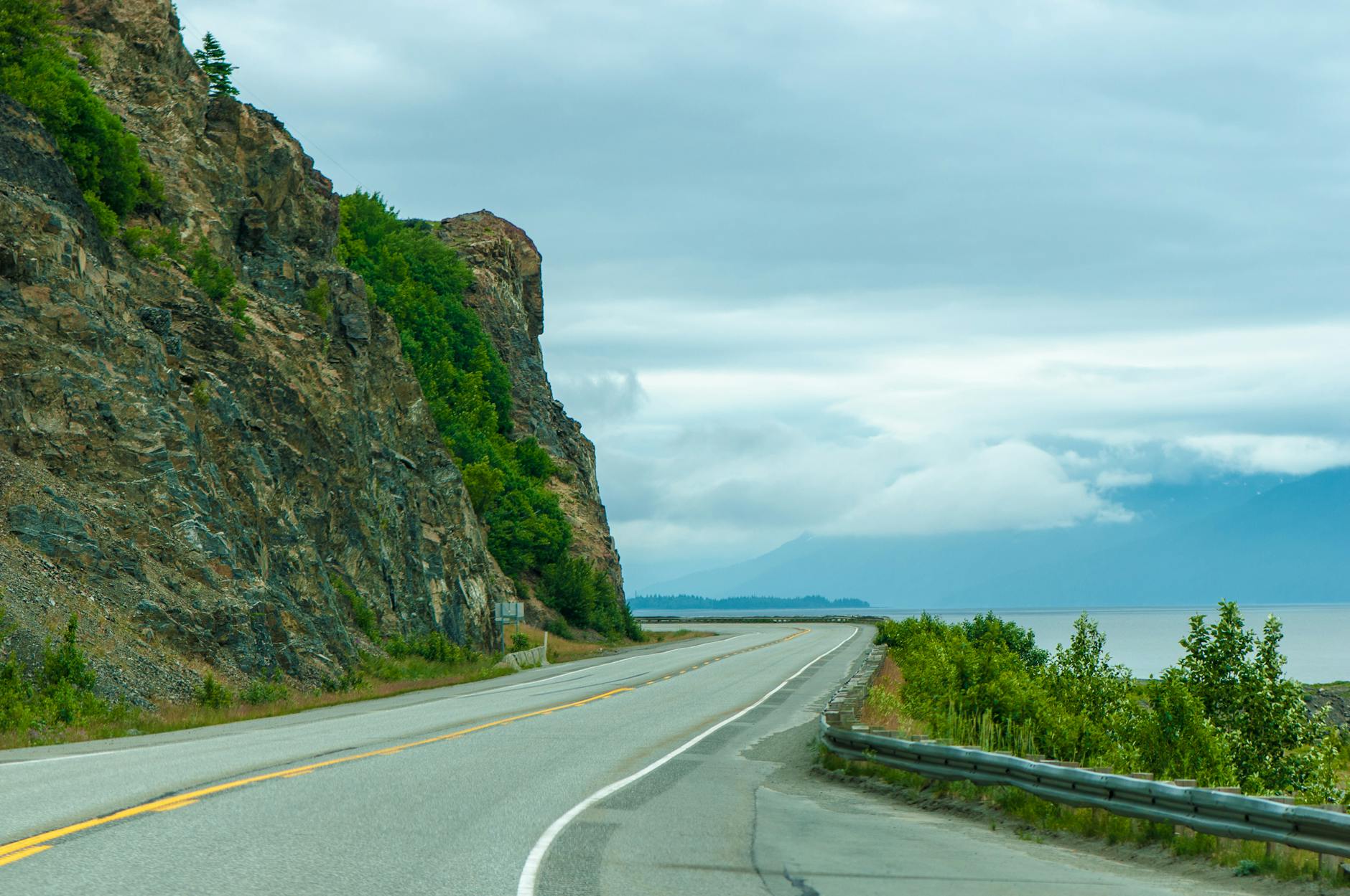 Pusta chorwacka szosa nad jeziorem u stóp skalistych klifów