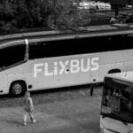 Monochromatyczne zdjęcie autobusu FlixBus na dworcu z pasażerami