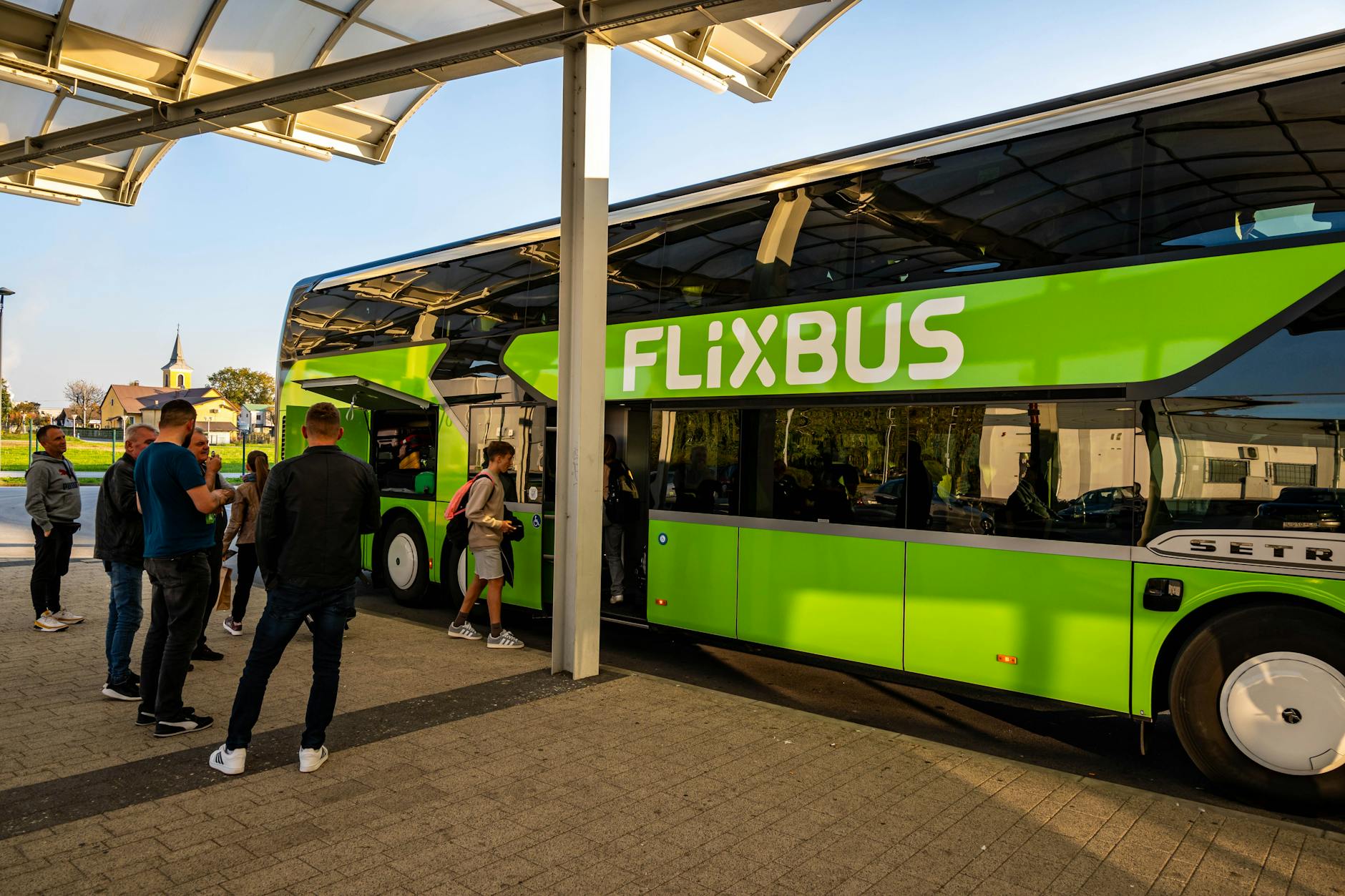 Pasażerowie wsiadają do zielonego autobusu FlixBus na dworcu w Chorwacji